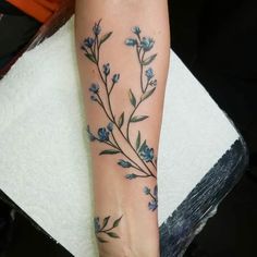 a woman's foot with blue flowers and leaves on the left side of her leg