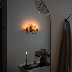 a candle is lit on the wall next to a vase with flowers and candles in it