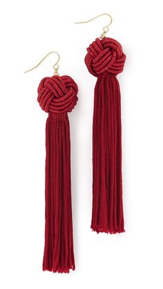 pair of red tasselled earrings with gold tone hooks and knoted ends on white background