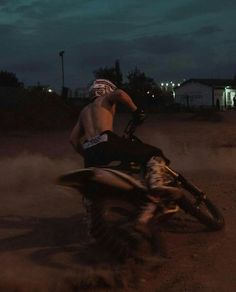 a man riding on the back of a dirt bike in the middle of the night