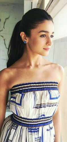 a woman standing in front of a window wearing a white and blue dress