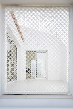 the interior of a building with white walls and latticed screens on the windowsill