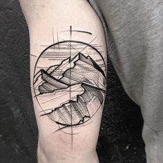 a man's arm with a mountain and circle tattoo on the left upper arm