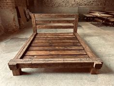 a bed made out of wooden planks in a room with brick walls and tables