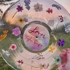 someone holding up a glass plate with flowers on it that says love is the sun