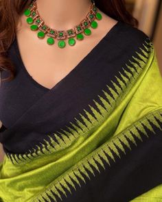 a woman wearing a green and black sari with gold accents on the neckline