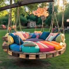 an outdoor swing bed made out of wooden pallets with colorful pillows on the top