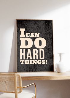 a black and white poster with the words i can do hard things next to a chair