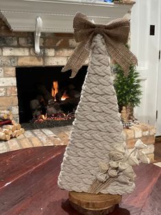 a white christmas tree sitting on top of a wooden table next to a fire place