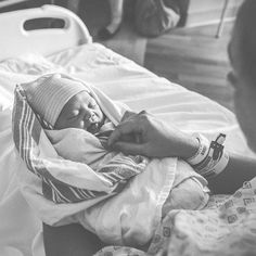 a woman holding a baby in her arms while laying on a bed with other people nearby