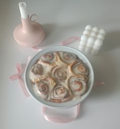 a bowl filled with cinnamon rolls on top of a table next to some marshmallows