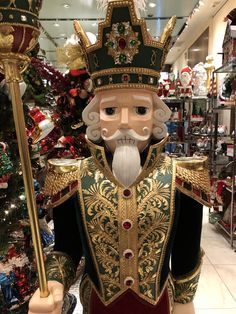 a statue of a king holding a staff in front of a christmas tree at a store