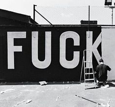 a man is painting the side of a wall with words painted on it in black and white