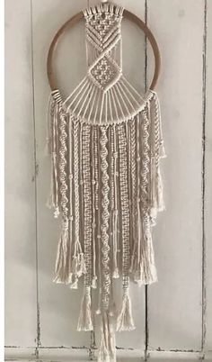 a white macrame hanging on a wall with tassels and beads around it