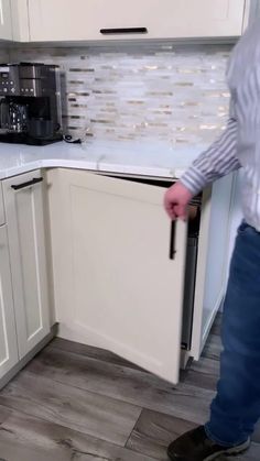 a kitchen with white cabinets and wood flooring on the counter top, next to a coffee maker