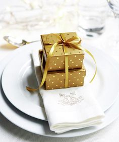 a stack of wrapped presents sitting on top of a white plate next to silverware