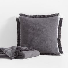 a gray pillow and some blankets on a white surface