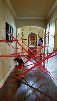 a boy is playing with red tape in the hallway