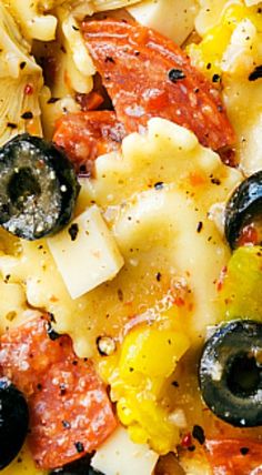 a close up view of some pasta with olives and peppers on it's surface