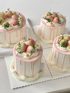 three cakes decorated with strawberries and daisies on top of each other, sitting on a table