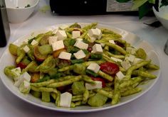 a white plate topped with green beans and veggies covered in feta cheese