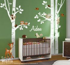 a baby's room with green walls and white tree decals