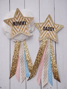 two stars with the words mommy and daddy written on them are hanging from white wood planks