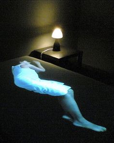 a person laying on a bed in the dark with a light shining on their leg