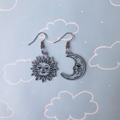 the sun and moon earrings are hanging from silver earwires on a blue background with white clouds