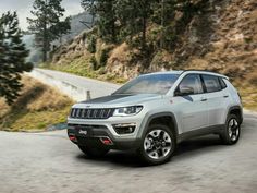a jeep compass driving down a road next to a mountain side with the words jeep compass 2017 written on it