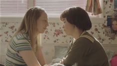 two young women sitting next to each other in a room with flowers on the walls