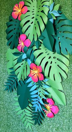 paper cut flowers and leaves laying on the ground with green grass in the foreground