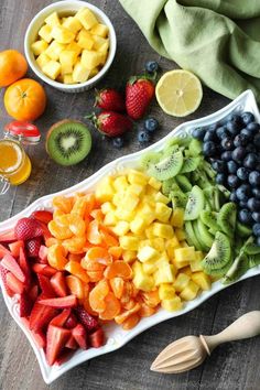 a platter filled with fruit next to bowls of oranges, kiwi and strawberries