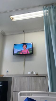 a flat screen tv mounted to the side of a wall above a bed in a room