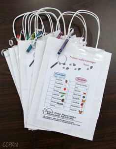 five white bags with writing on them sitting on a wooden table next to pens and markers