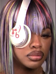 a close up of a person with headphones on their ears and hair dyed multicolored