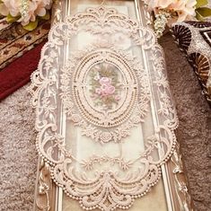 an ornate mirror with pink flowers on the floor next to rugs and other decorative items