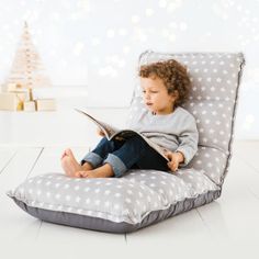 a little boy sitting on a bean bag chair reading a book