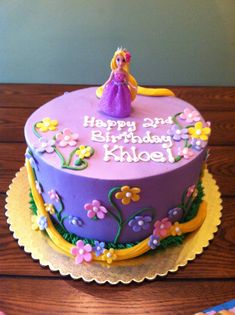 a purple birthday cake with a princess figure on top and flowers around the edges, sitting on a wooden table