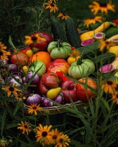 a basket filled with lots of different types of fruits and vegetables next to yellow flowers