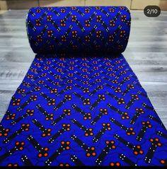 a blue cloth with orange and black dots on it, sitting on top of a wooden floor