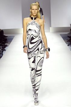 a woman walking down a runway wearing a dress with black and white designs on it