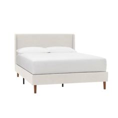 the bed is made up with white linens and wood legs, but it has no headboard