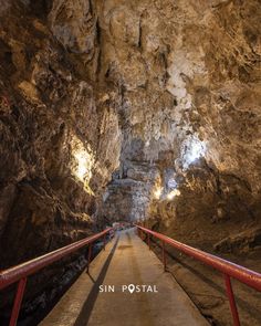 the walkway leading to an underground cave with red railings and light at the end