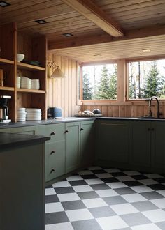 a kitchen with black and white checkered flooring, green cabinets and open shelves