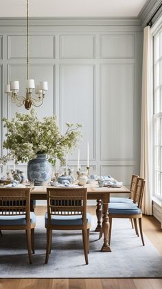 a dining room table with blue chairs and a vase filled with flowers on top of it