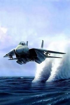 a fighter jet flying over the ocean with water splashing from it's bottom