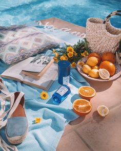 an open book and some oranges on a towel next to a pool