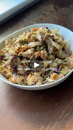 a white bowl filled with food sitting on top of a wooden table next to a laptop