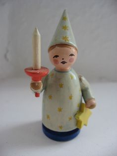 a small figurine with a candle in it's hand on a white surface